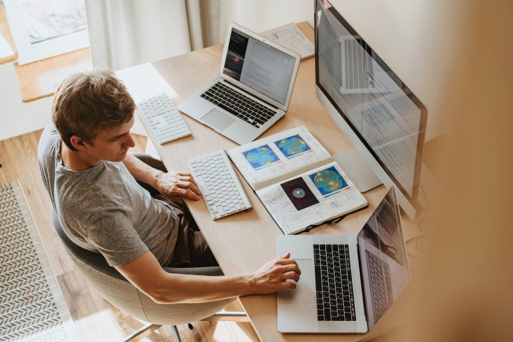 hire an editor - image depicts man sitting at desk with multiople screens